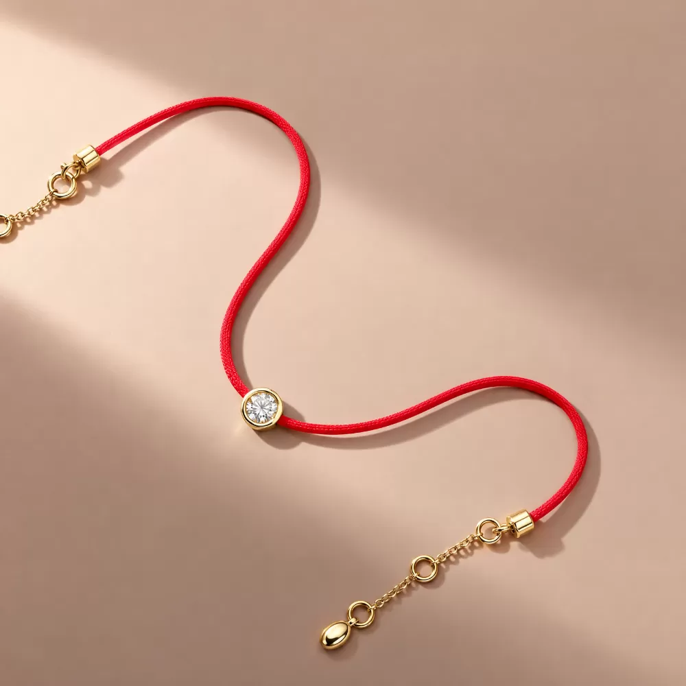 Pulsera de hilo rojo en oro amarillo con diamante talla brillante.